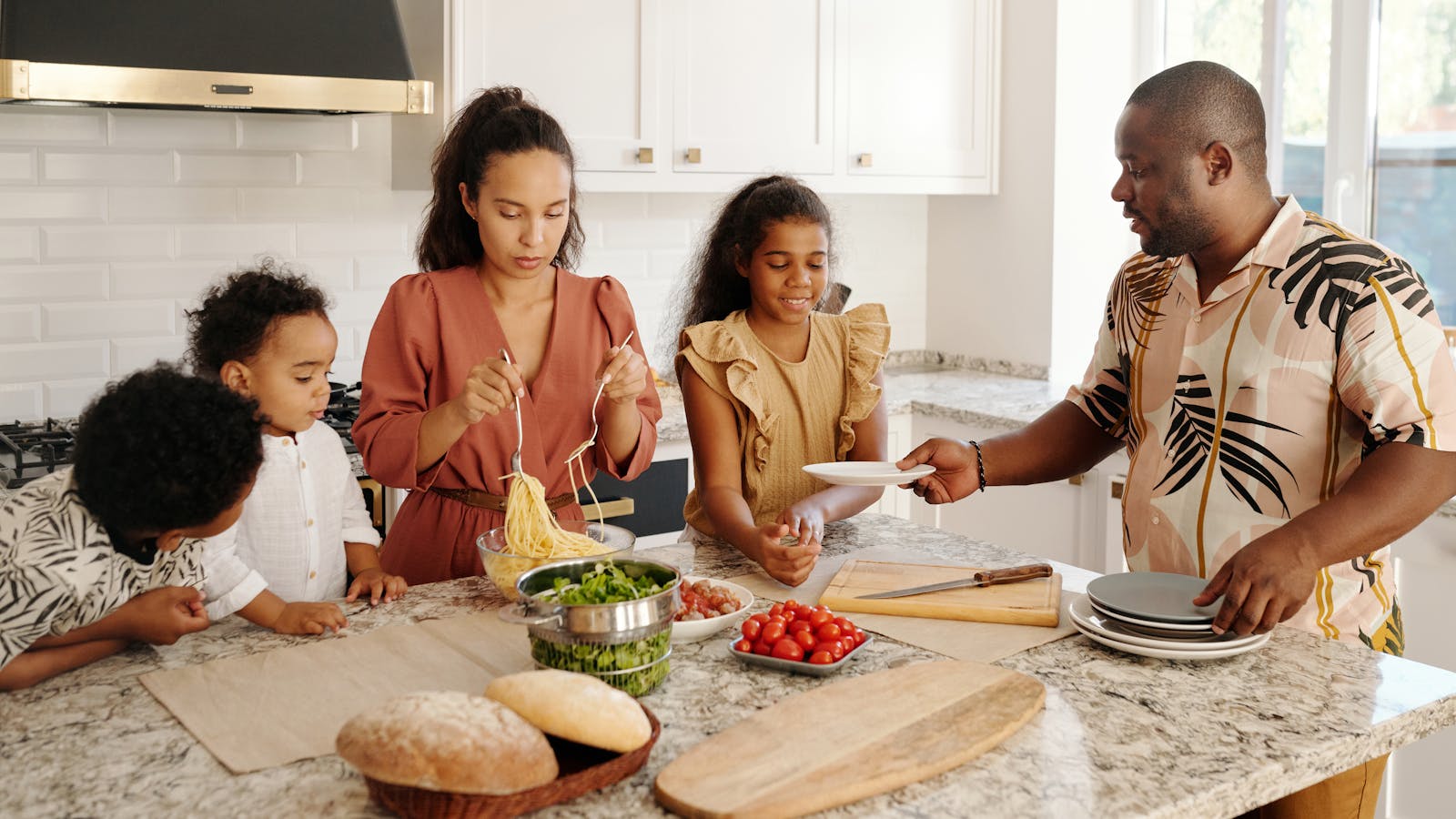 Parents and children preparing food together in a kitchen